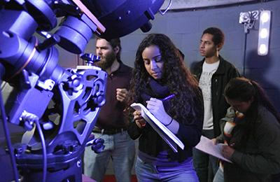 student in observatory looking through telescope